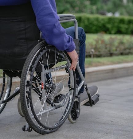 Individual in a wheelchair on a paved walkway outdoors, showcasing mobility and independence.